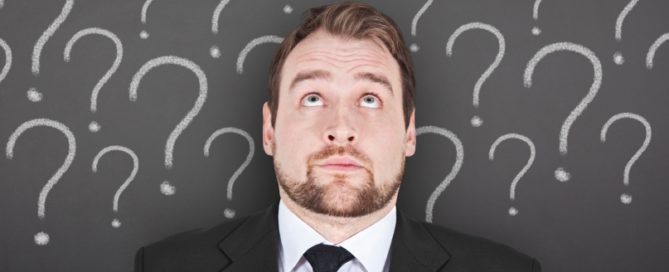 A business professional in a suit and tie surrounded by question marks
