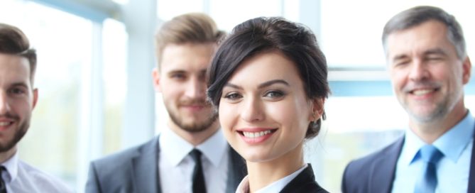 four smiling professionals in an office